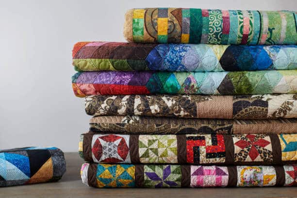 Quilts stacked on white wall background