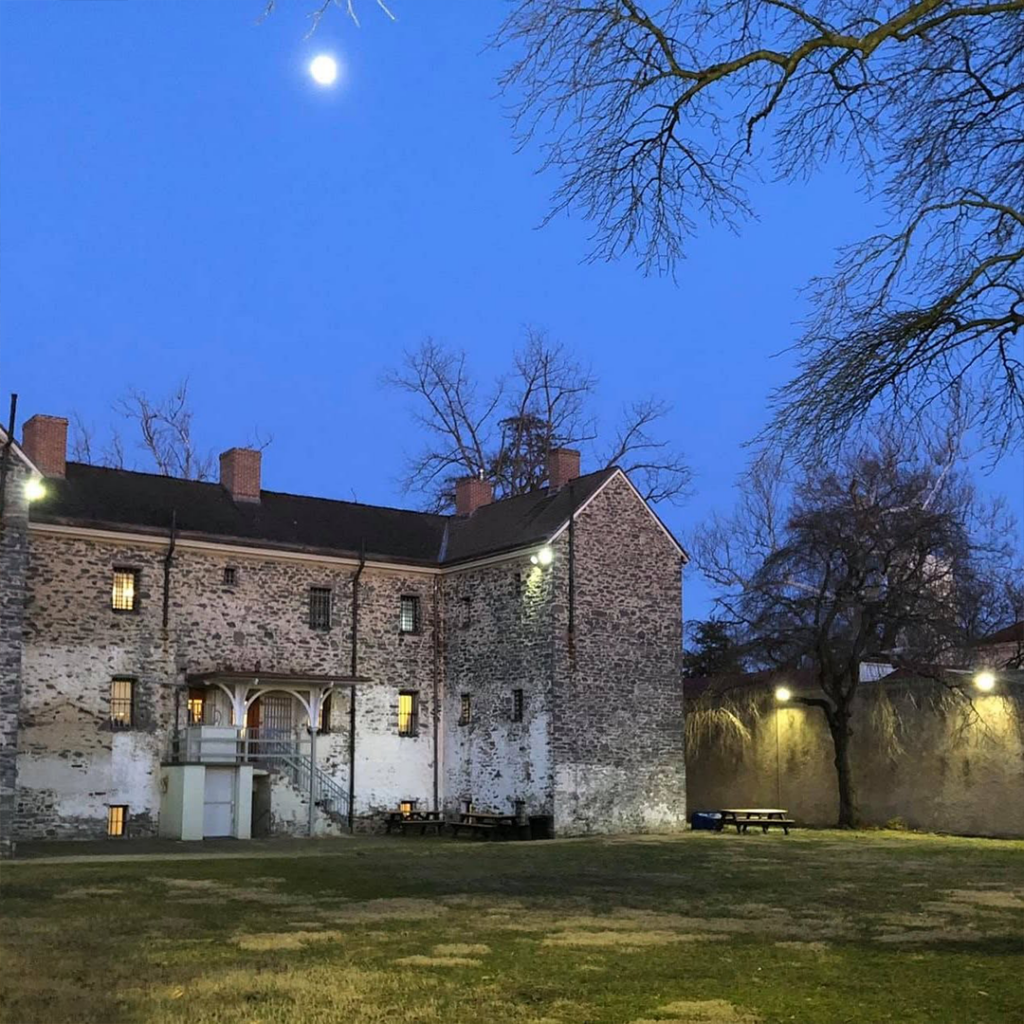 Image of the Burlington County Prison Museum at night with a moon shining bright in the sky